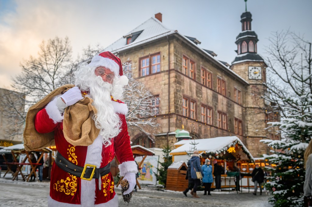 Weihnachtsmann vor Weihnachtsmarkt-Stand