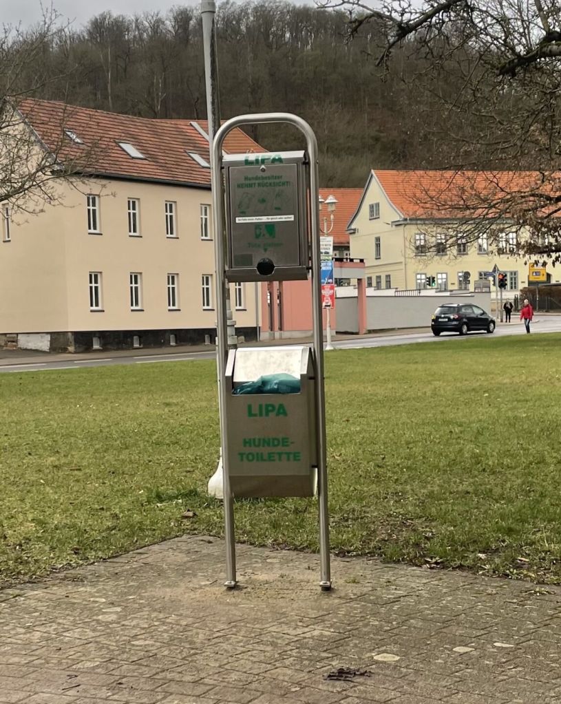 Der Spender für Hundekotbeutel steht auf der Grünfläche Hinter der Mauer in Eisenach.