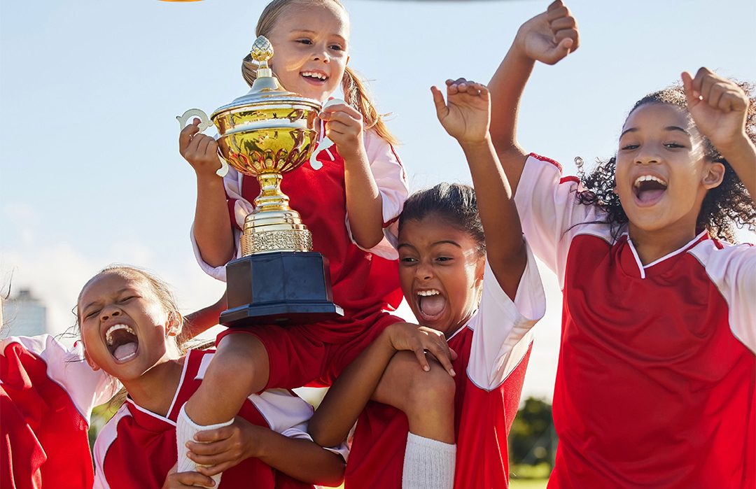 Junge FuÃŸballerinnen freuen sich und halten einen Pokal in die HÃ¶he (Symbolbild)